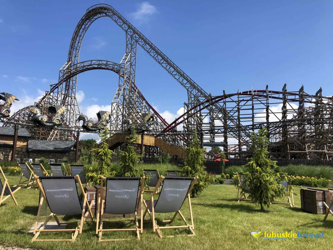 Widok na rollercoaster w parku rozrywki Energylandia w Zatorze, z leżakami na trawie.
